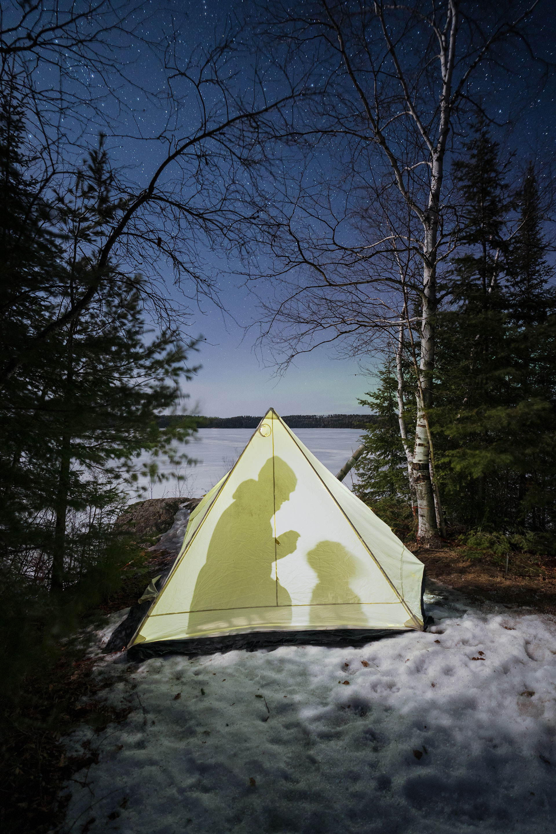 person silhouetted inside a tent while winter camping in Quetico