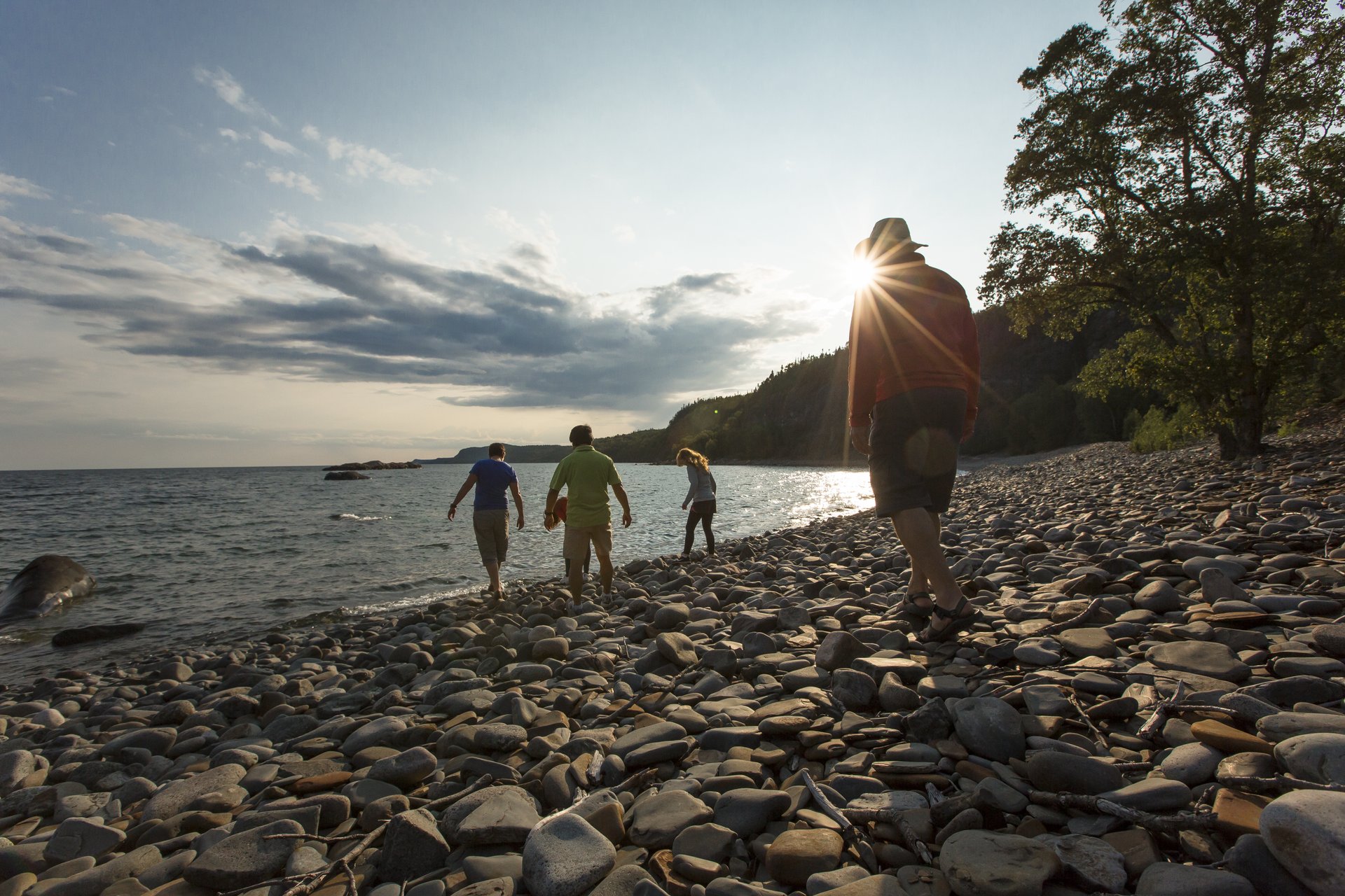 a family walks along a pebbly beach