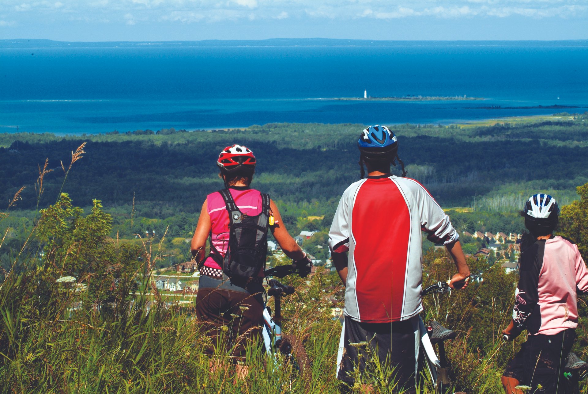 three cyclists take in the views of Georgian Bay from the top of Blue Mountain