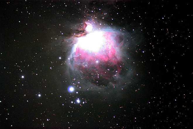 the Orion Nebula; a bright white flare in space, surrounded by swirls of purple light and dots of stars of various sizes.
