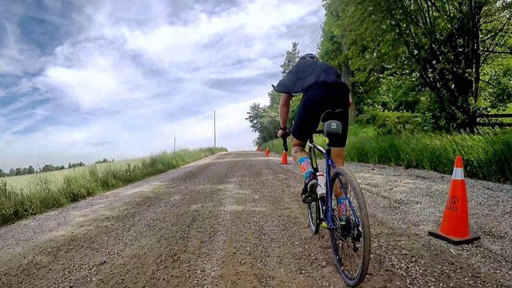 Cyclist on road bike peddling down a gravel country road.