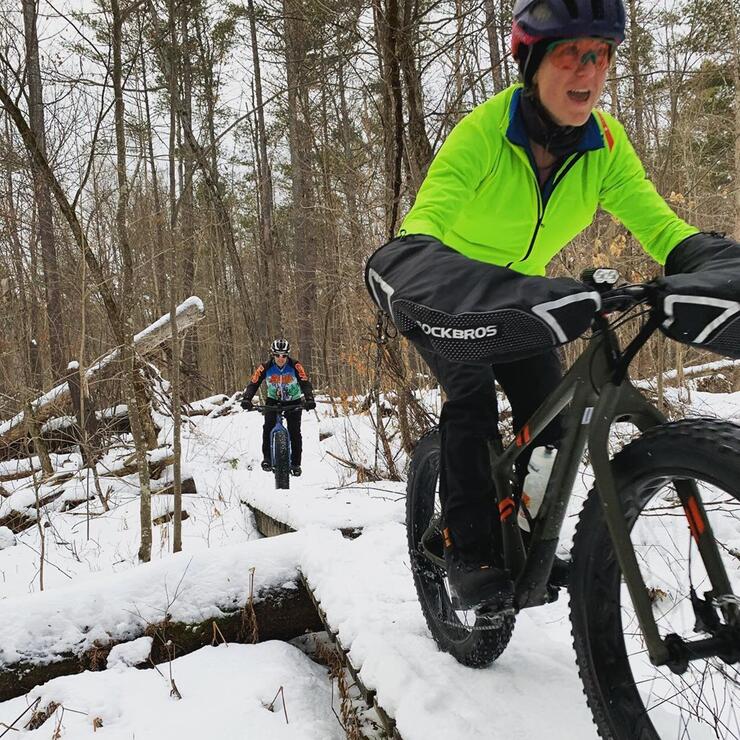 A laughing person riding a fat bike in snow.