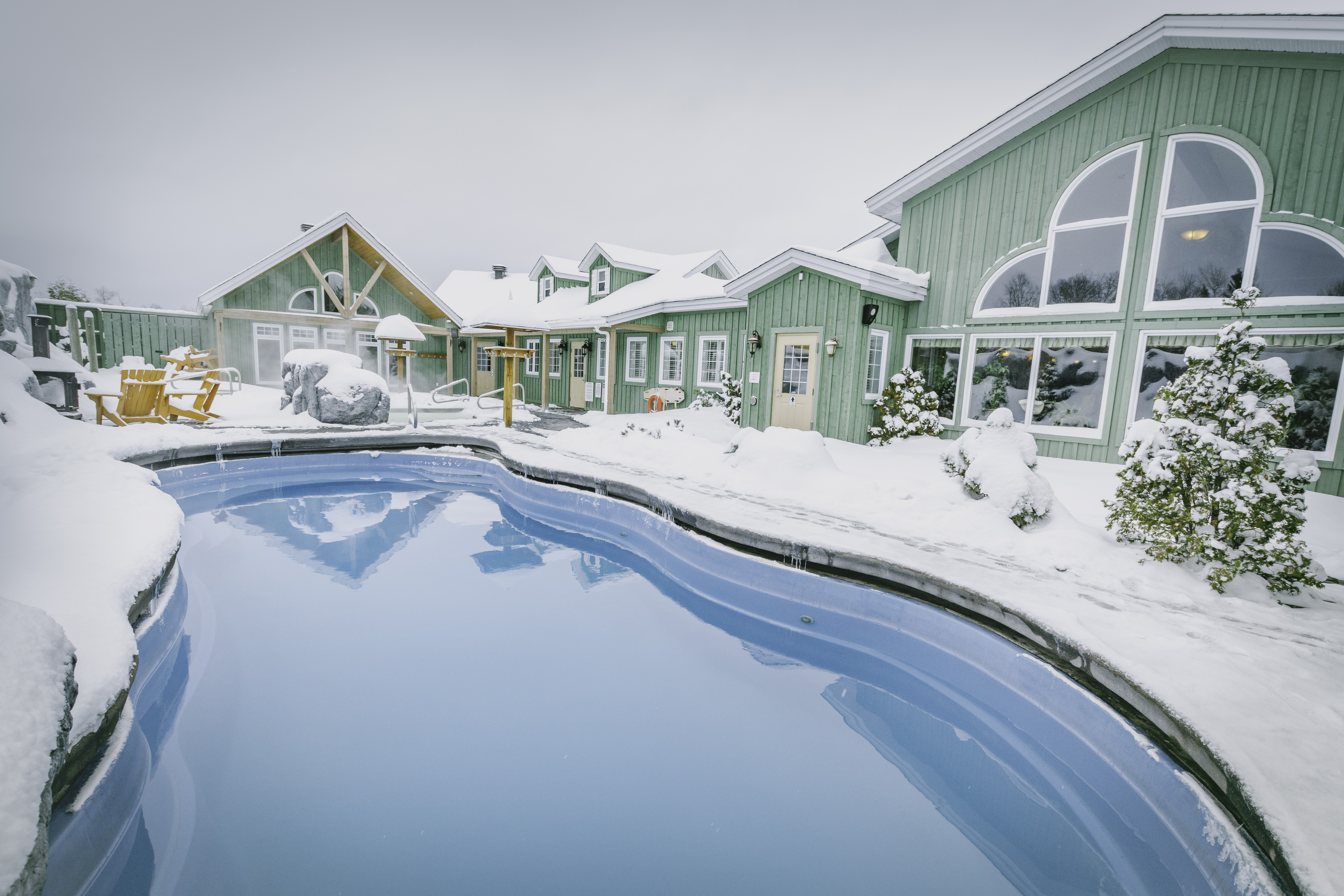 A blue spa pool surrounded by snow. 