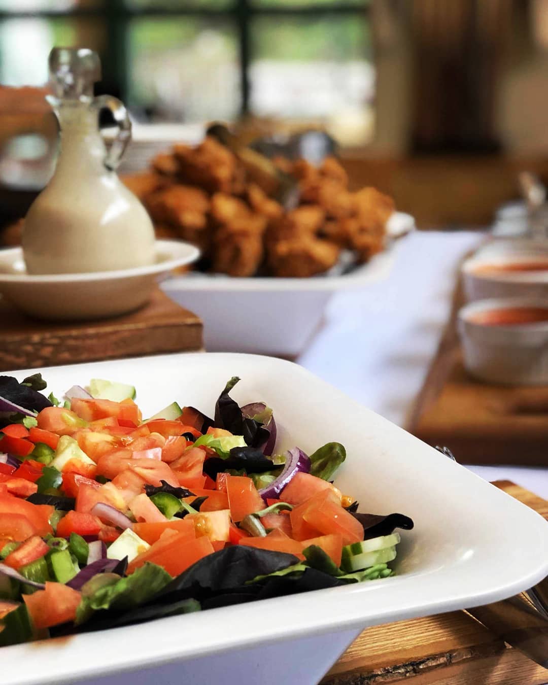 A delicious-looking salad and chicken wings laid on a wooden table at Elk Lake Lodge