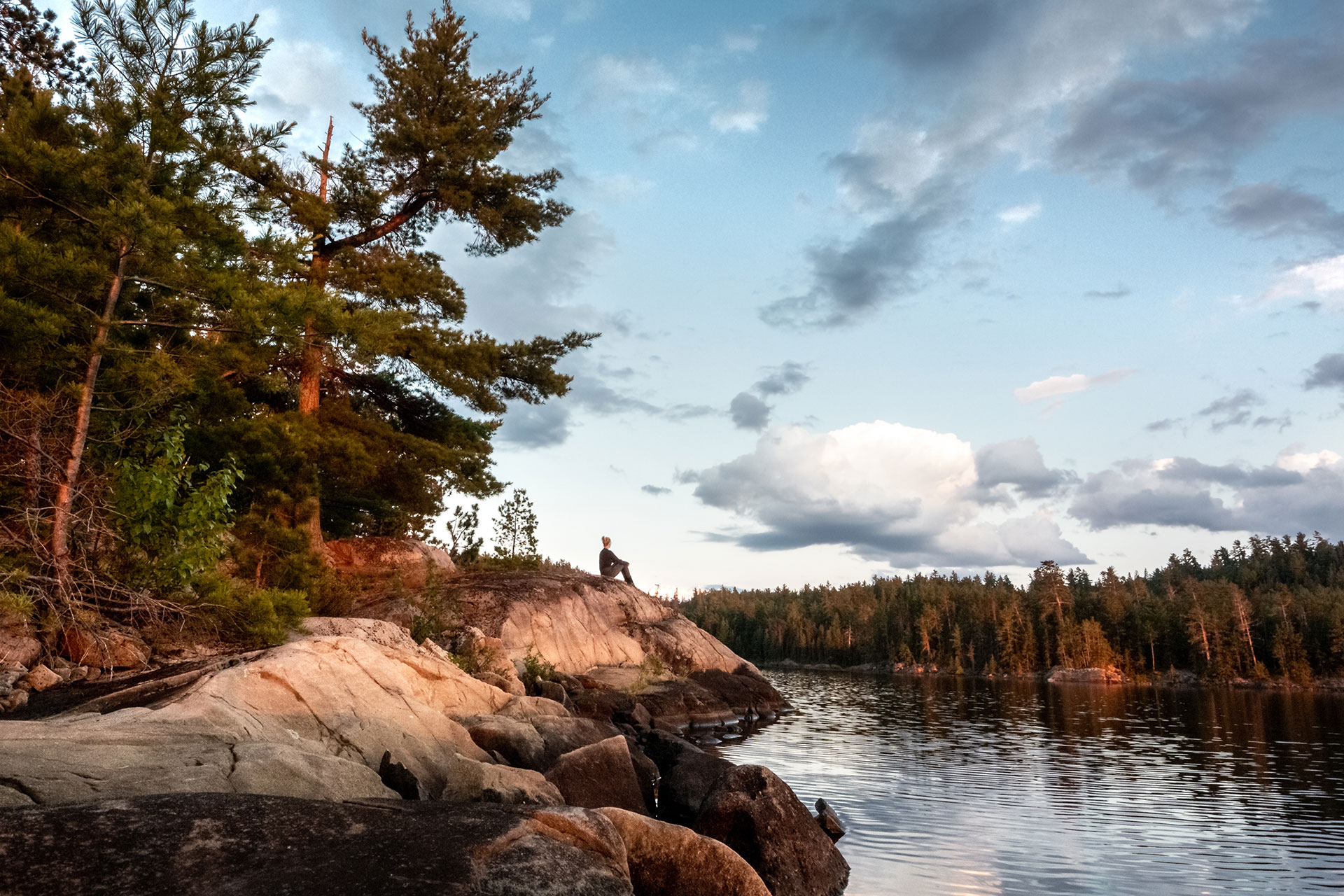 a person sits on a rock overlooking the Obabika River at dusk