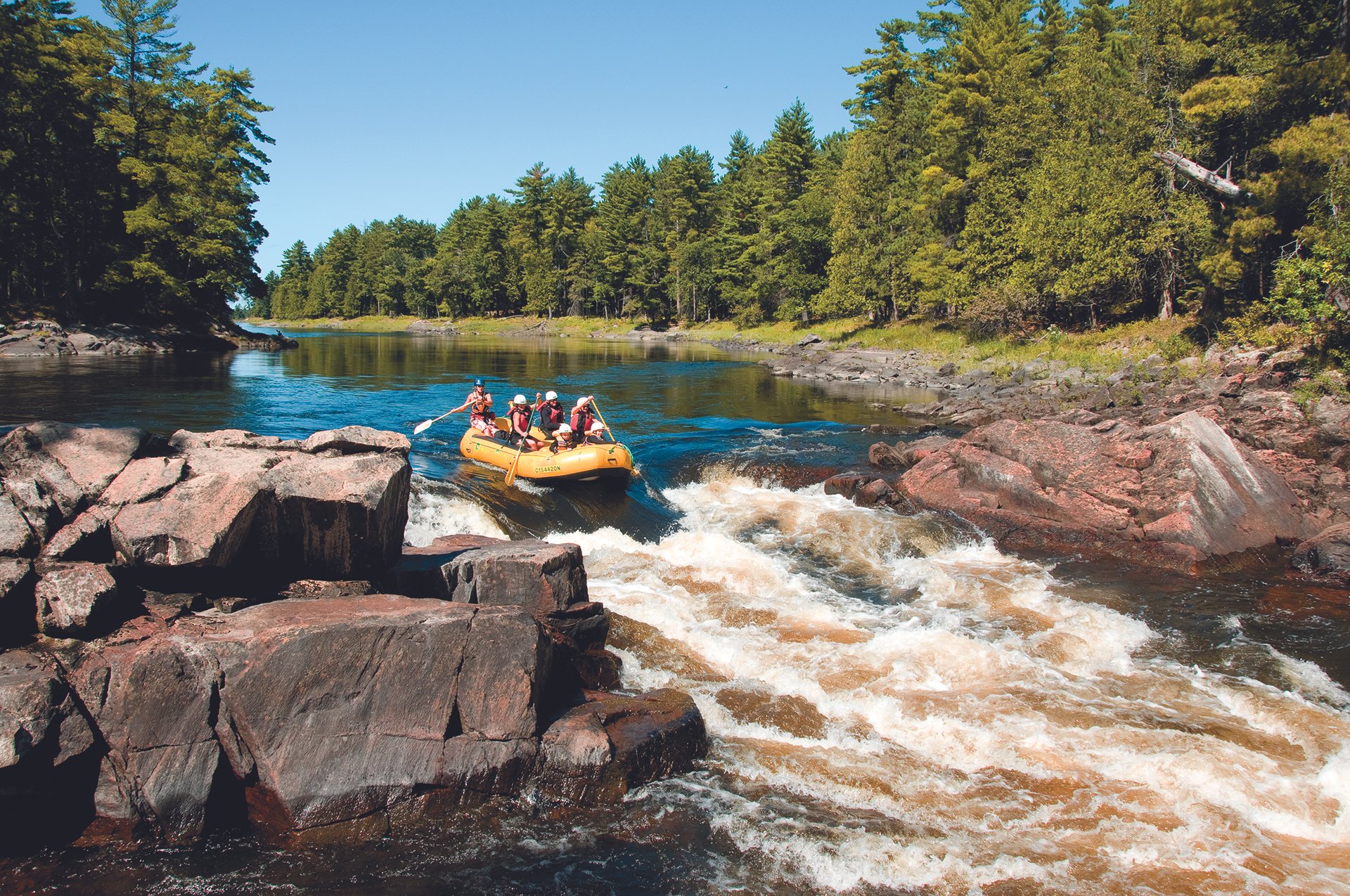 a group whitewater rafting into a set of rapids