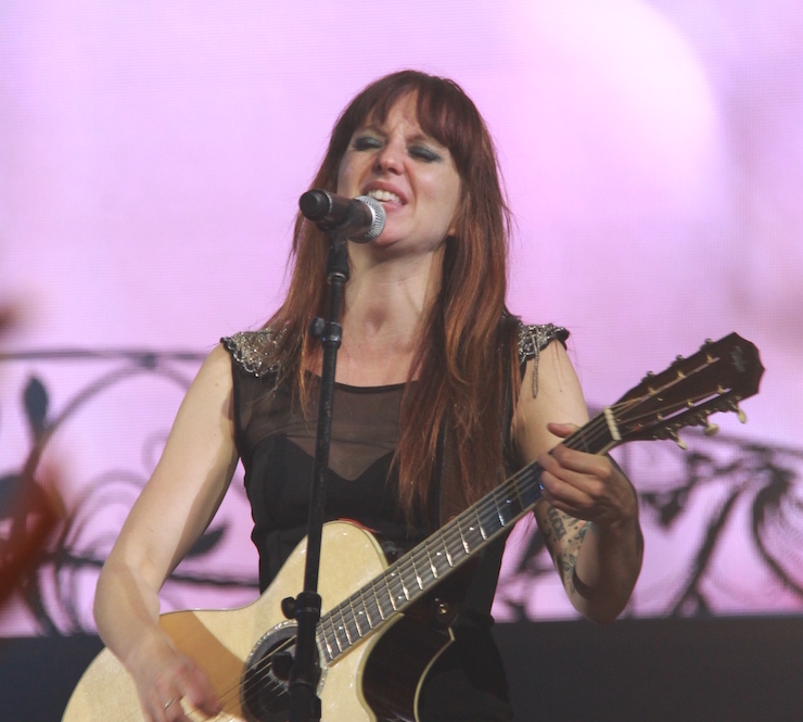 Woman singing into microphone and playing guitar