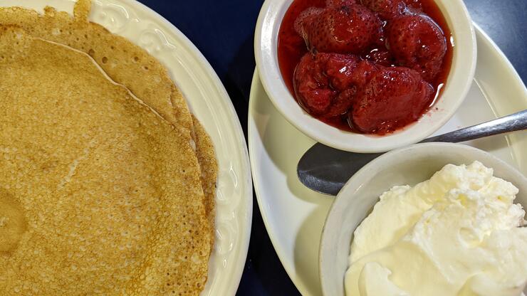 delicious-looking Finnish pancakes with bowls of strawberries and cream