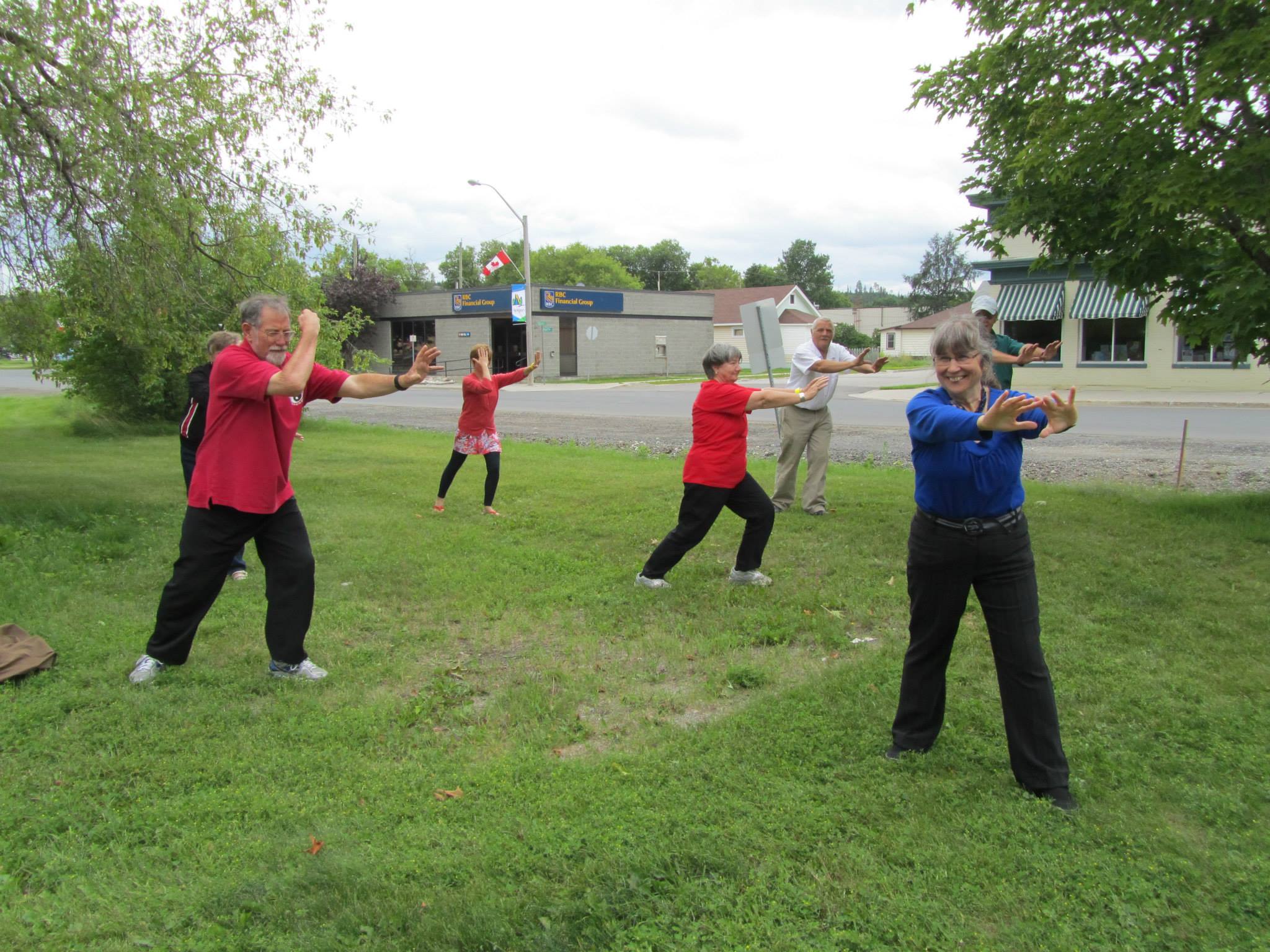 smiing people doing Tai Chi in a lush green park at the Nipigon Blueberry Blast Festival