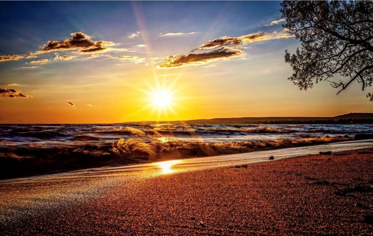 A sandy beach at sunset with some light clouds. 