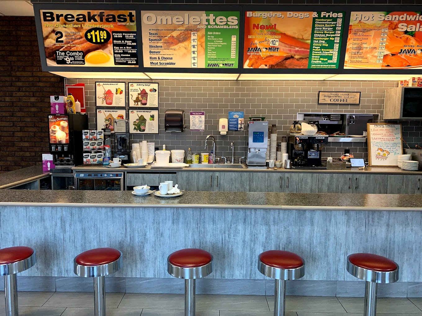 Java Hut; a clean, shiny glass breakfast bar bordered with red stools and a light-up menu board behind the counter listing an ample breakfast menu.