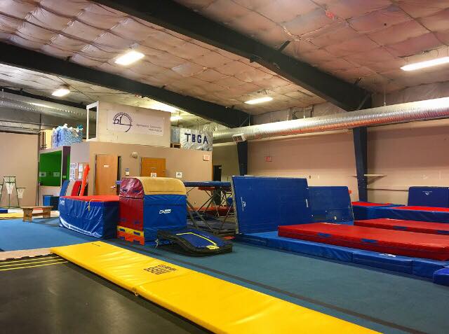 gymanstics mats and jumping apparatuses with a sign that says "TBGA". 