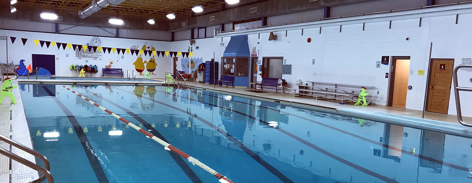 The interior of Churchill Pool in Thunder Bay; a large indoor swimming pool with lanes and toys.