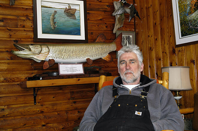 Vermilion Bay Lodge owner Gord Bastable sits in front of a wooden replica of the biggest muskie caught in Eagle Lake â a 61-pounder Edward Walden caught in 1940.