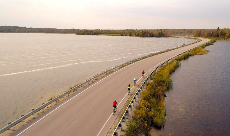 Group of cyclists riding on a paved causeway.
