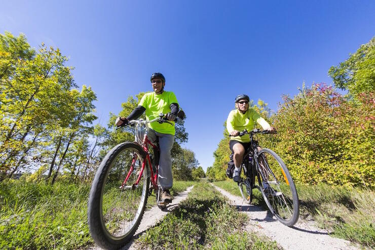 Two men riding bikes on dirt trail. 