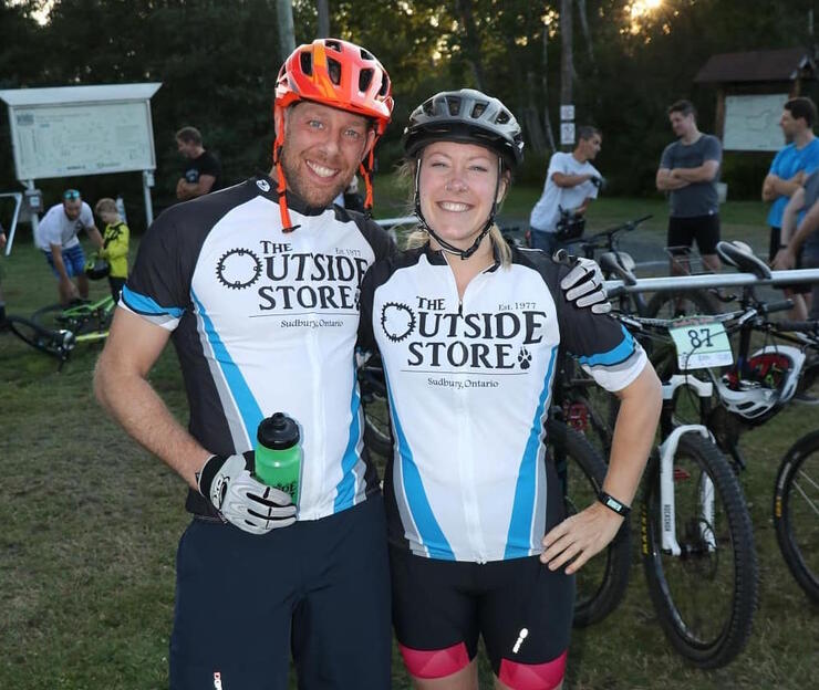 Two smiling people with The Outside Store shirts on.