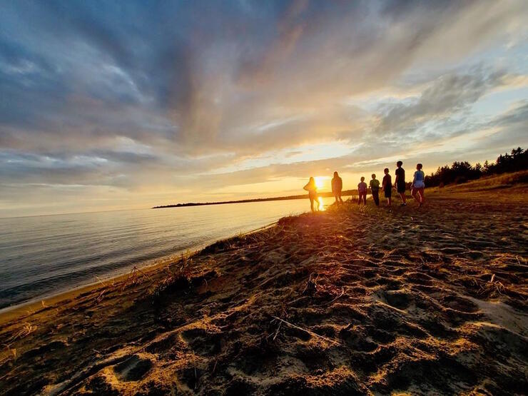 People walking on a beach at sunset.
