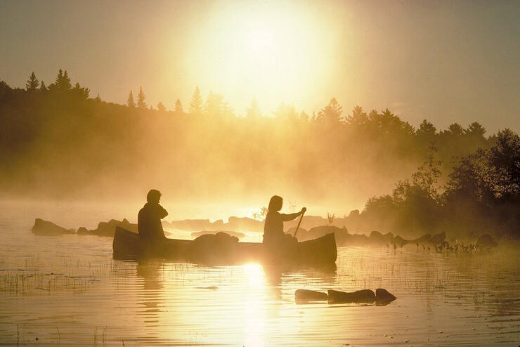 Two people paddling a canoe in early morning mist