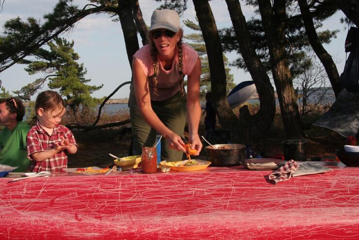 Woman and child eating lunch, using upside down canoe as a table