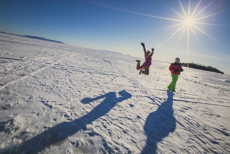 Girl jumping in air on frozen lake. 