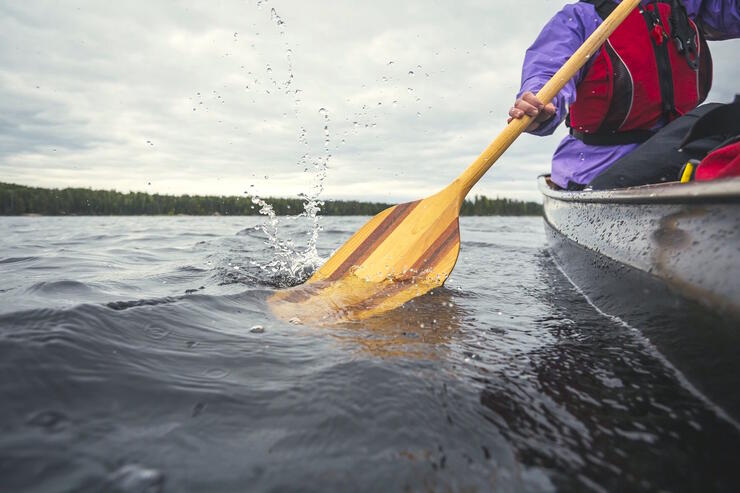 Close up of a wooden paddle in the water.