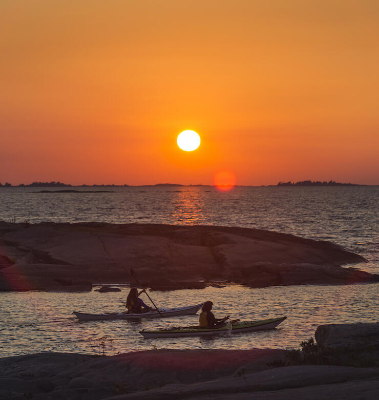 Two kayakers paddling at sunset 