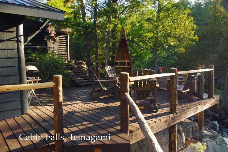 Large wooden deck around a rustic cabin.
