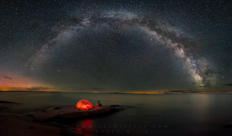 Glowing orange tent in front of the milky way in the night sky.