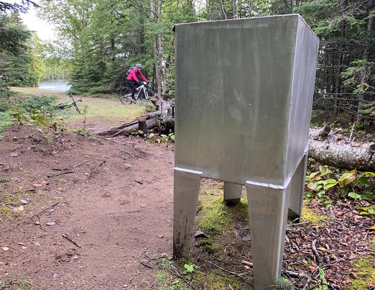 Bear proof garbage container on a wooded campsite.