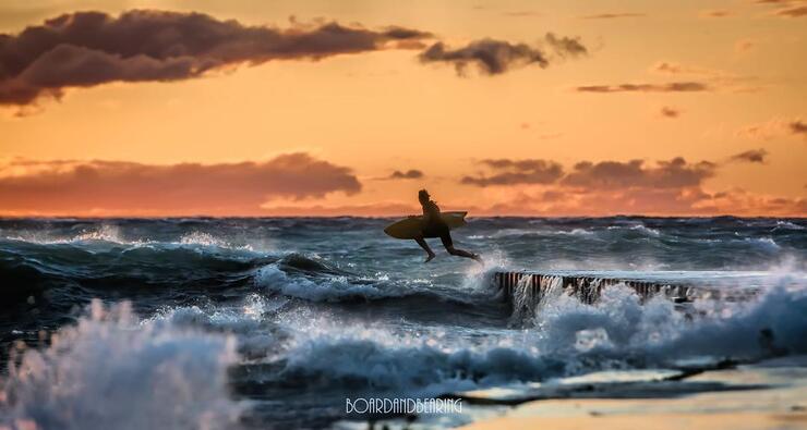 Man surfing big waves at sunset.