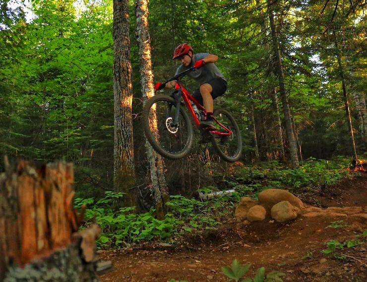 Man on mountain bike high in air after a jump in forest