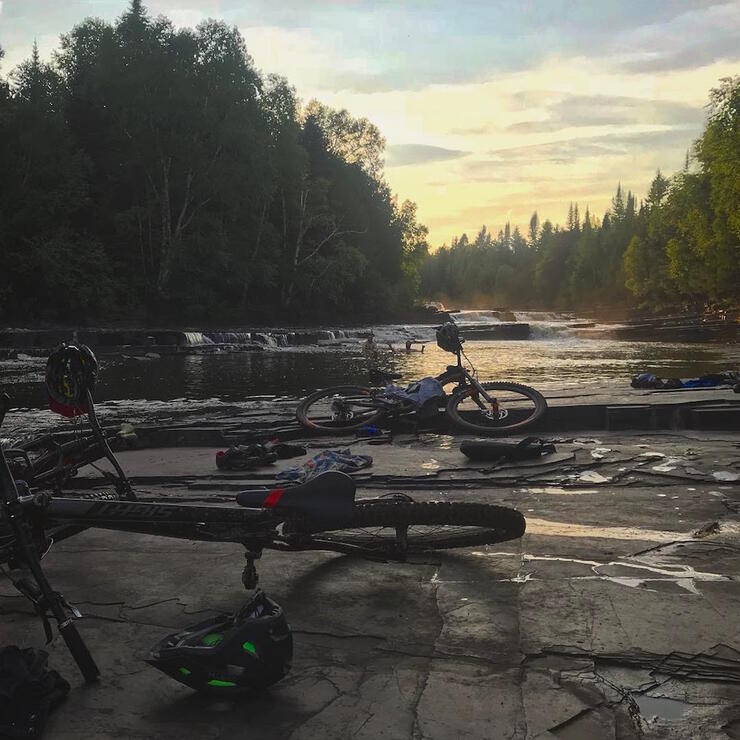 Group of mountain bikes laying flat on rocks in front of a river