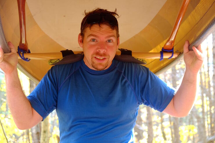 Close up of a man portaging a canoe.