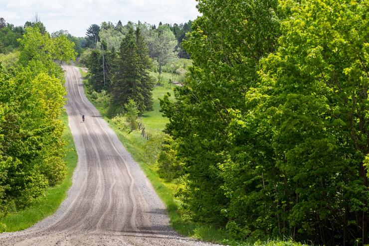 Long gravel road with cyclist in distance.