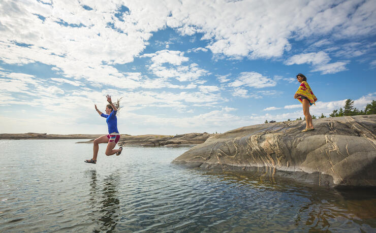 Woman jumping off rock into the water