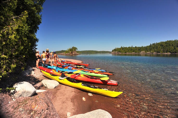 A group of kayaks and kayakers on the shore of Lake Superior. 