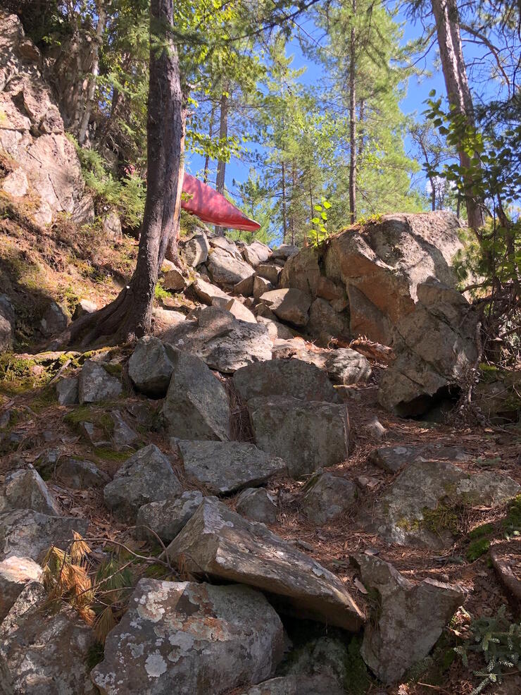 Person portaging a canoe up large boulder path up a hill