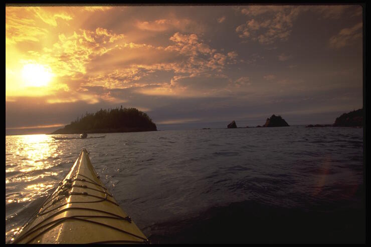 Bow of a kayak on Lake Superior at sunset.