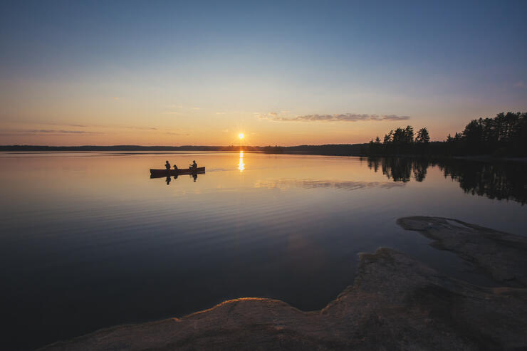 Canoe paddling on a lake at sunset