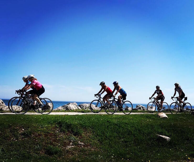 Group of cyclists riding along the lake.