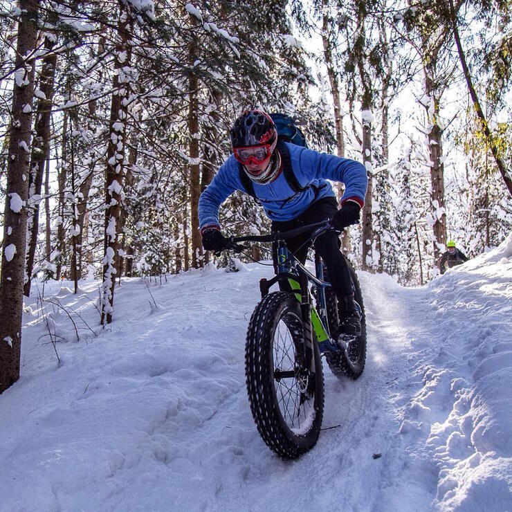 Person on a fat bike going down a small snow covered hill. Fat biking is one of the many winter activities in ontario.