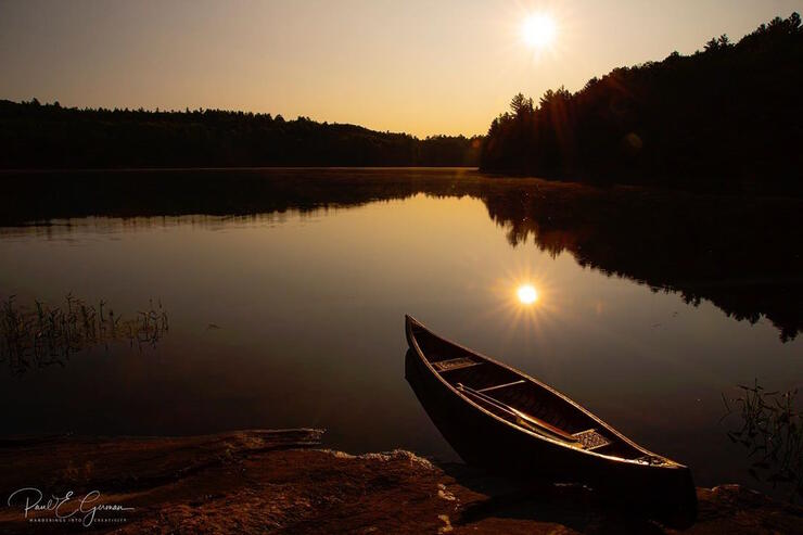 Canoe on a serene lake at sunset.
