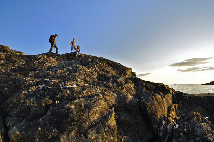 Woman and two children hiking on top of rocky cliff