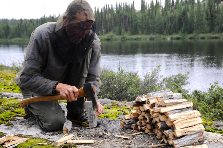 Man in a bug jacket chopping wood. 