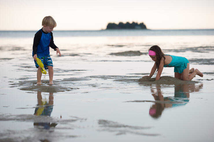 A young boy and girls playing in the shallow water on a beach. 