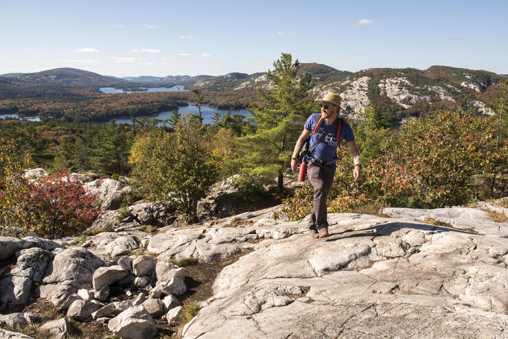 Man hiking on white rocks with beautiful lake in background.