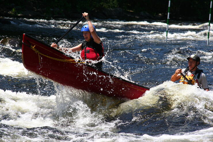 Man and woman paddling a canoe in whitewater.