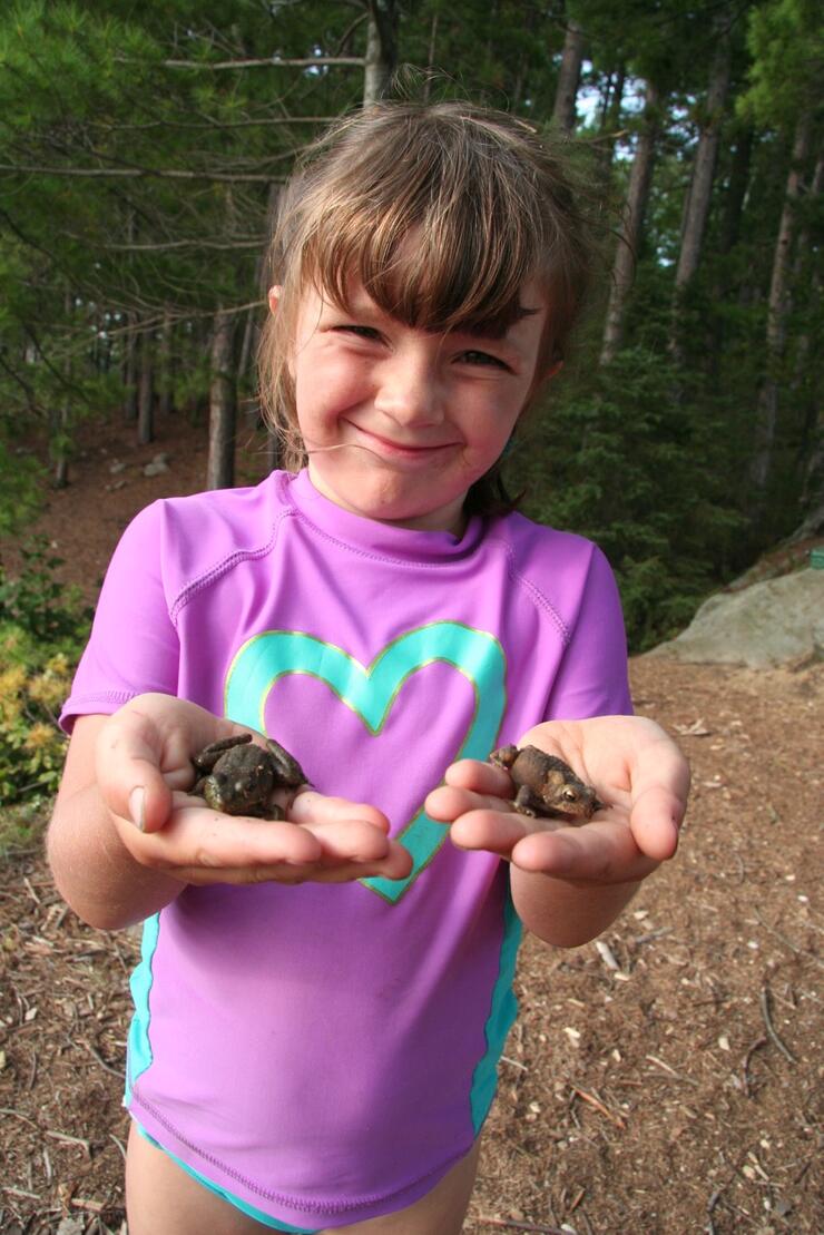 Young girl holding two frogs