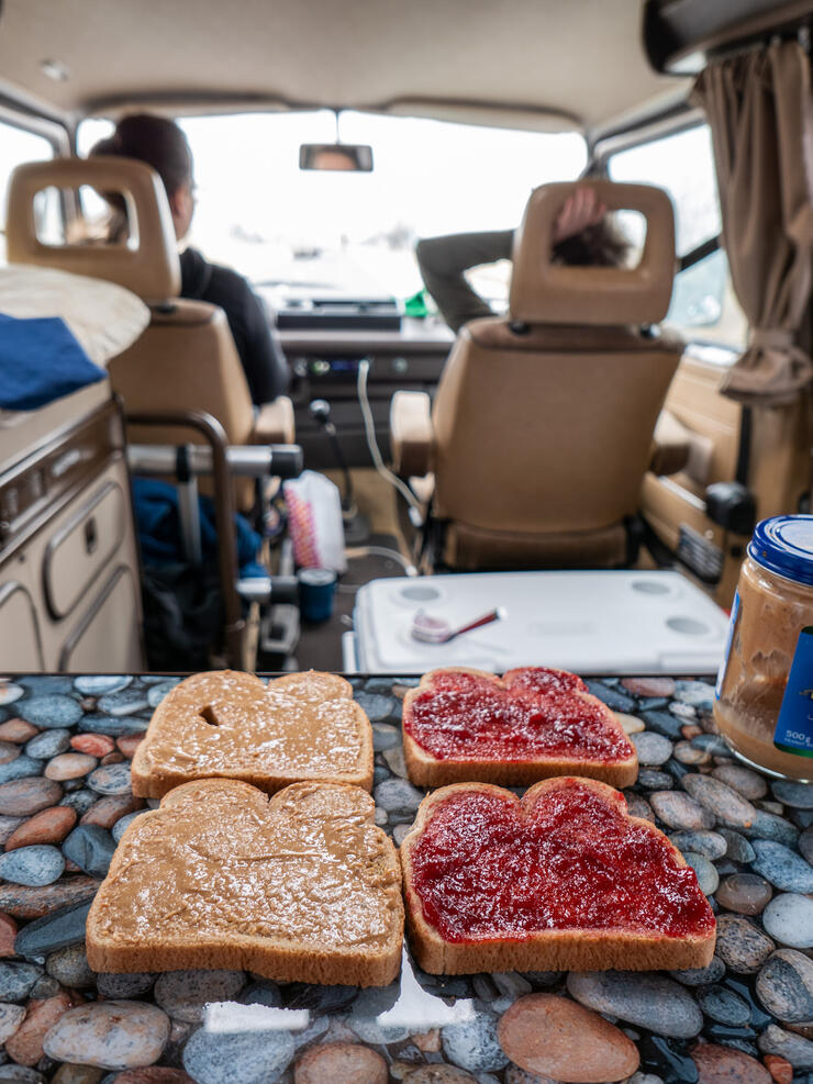 Peanut butter and jam sandwiches on a table in a camper van. 